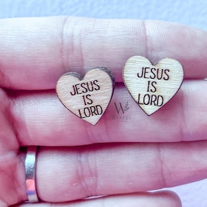 May include: Two wooden heart-shaped ornaments with the text "Jesus is Lord" on each. The ornaments are held in a person's hand.