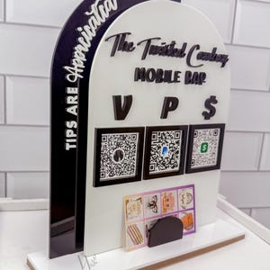 May include: A white and black acrylic mobile bar tip sign with the text "TIPS ARE APPRECIATED" and "The Twisted Cowboy MOBILE BAR". It features QR codes for payment and a small display for business cards.