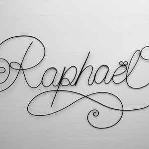 Peut inclure: Sculpture en fil de fer noir du nom "Raphaël" avec une touche décorative à la fin.