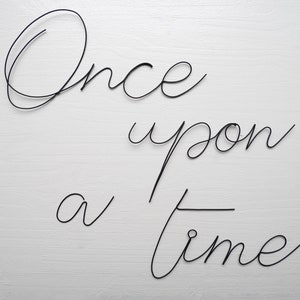The phrase "Once upon a time" in annealed wire, writing, message in wire, wire phrase, wire quote, wire wall decor