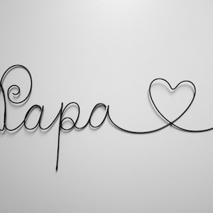 Puede incluir: Escultura de alambre negro del arte de la palabra "Papa" con un corazón al final.