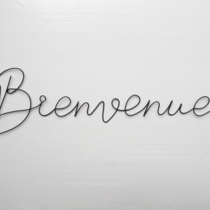 May include: Black wire sculpture of the word "Bienvenue" on a white background.
