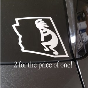 May include: A white vinyl sticker of the state of Arizona with a stylized Native American dancer inside the outline of the state. The sticker is on the back window of a black car. The text "2 for the price of one!" is below the sticker.