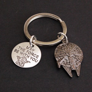 May include: Silver keyring with a charm that says "May the Force be with you" and a Yoda image. The second charm is a silver Millennium Falcon.