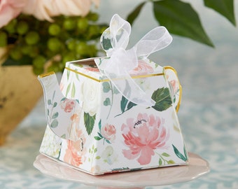Op de afbeelding: Een theepotvormig papieren doosje met een witte achtergrond en een aquarel bloemenpatroon in roze, perzik en groene tinten. Het doosje is afgewerkt met een goudkleurige rand en een transparant wit organza lint dat bovenop is gestrikt.