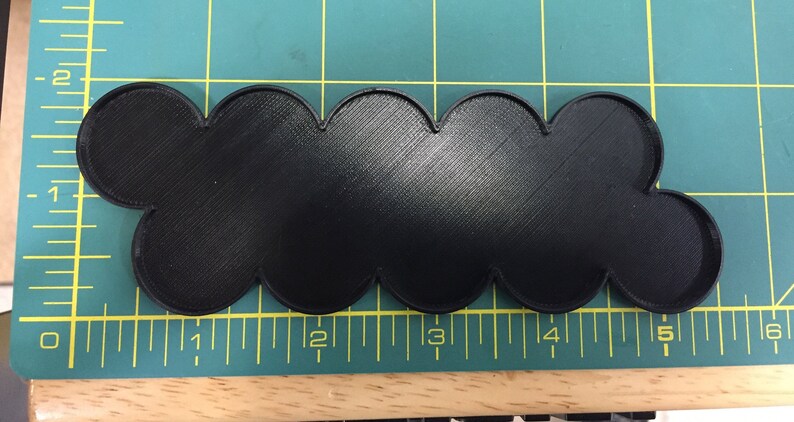 Op de afbeelding: Zwarte plastic basis met een gegolfde rand, ongeveer 12,7 cm lang. De basis is ontworpen om miniatuurfiguren of andere kleine voorwerpen te houden.