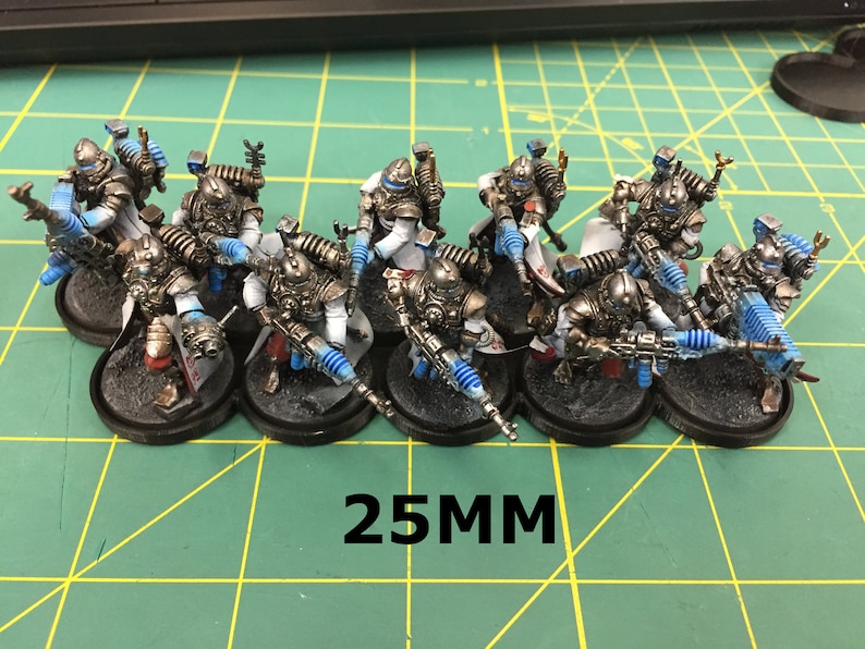 Op de afbeelding: Een groep van tien 25 mm miniatuurfiguren geverfd in zilver, wit en blauw. De figuren houden wapens vast en staan op zwarte bases.
