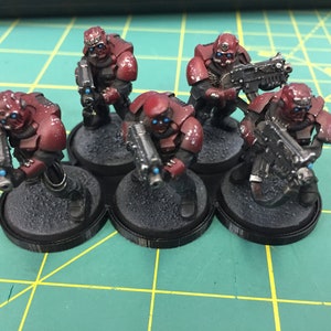 May include: Five red and black miniature figures holding weapons, standing on black bases. The figures are painted with a red and black color scheme.