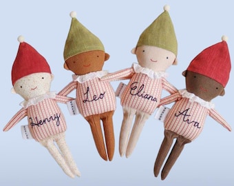 Può includere: Quattro bambole in tessuto morbido con cappelli a punta, che indossano camicie a righe ricamate con i nomi Henry, Leo, Eliana e Ava. Ogni bambola presenta un colletto a balze, tratti del viso semplici e una piccola etichetta bianca Bokuno.