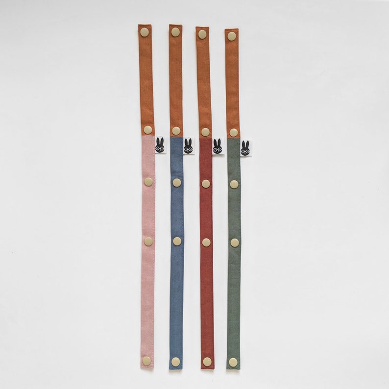 Pu&ograve; includere: Cinque cinturini in tessuto colorati con chiusure a scatto. Ogni cinturino ha un colore diverso: rosa, blu, rosso e verde. La parte superiore di ogni cinturino &egrave; in materiale simile alla pelle marrone. Ogni cinturino ha una piccola etichetta con un coniglietto con gli occhiali.