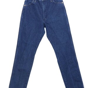 May include: Dark blue denim jeans with a classic straight-leg fit. The jeans have a button and zip closure, front and back pockets, and gold-coloured rivets. The garment is hanging on a metal hanger against a white background.