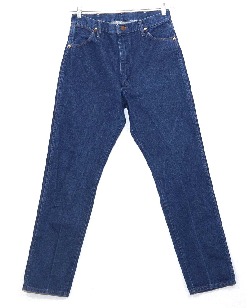May include: Dark blue denim jeans with a classic straight-leg fit. The jeans have a button and zip closure, front and back pockets, and gold-coloured rivets. The garment is hanging on a metal hanger against a white background.
