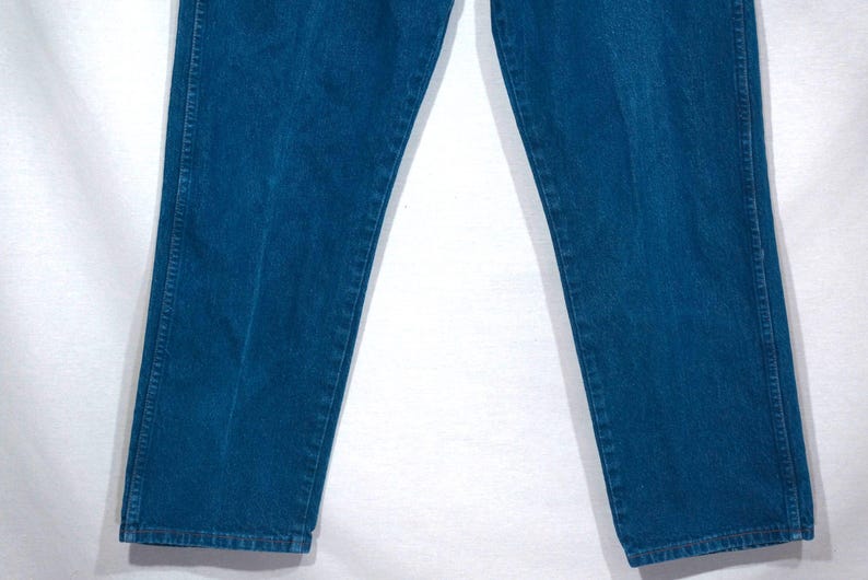 May include: A pair of blue denim jeans. The jeans are a medium wash, with visible seams and a classic straight-leg fit. The fabric appears to be sturdy and durable, suitable for everyday wear. The image shows the lower portion of the pants.