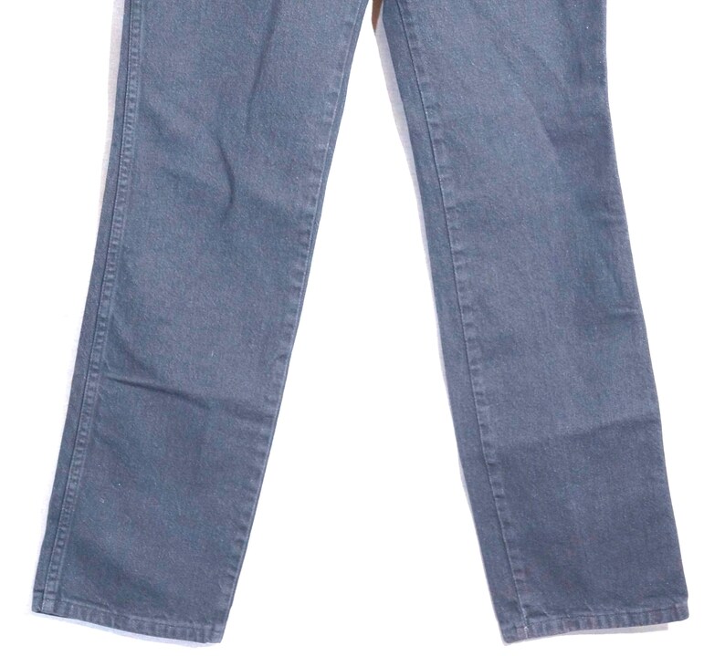 May include: A pair of faded blue jeans. The jeans have a classic five-pocket design, with a straight leg cut. The denim appears to be pre-worn, with subtle fading and wear marks. The jeans are a versatile wardrobe staple.