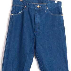 May include: A pair of blue denim jeans with a classic five-pocket design. The jeans feature copper-colored rivets and a button closure. The denim has a medium wash and a straight leg cut.