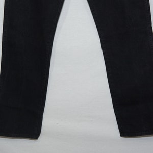 May include: A pair of black denim jeans. The jeans have a classic five-pocket design, with a straight leg cut. The fabric appears to be a medium-weight denim, suitable for year-round wear. The jeans are a solid black color.