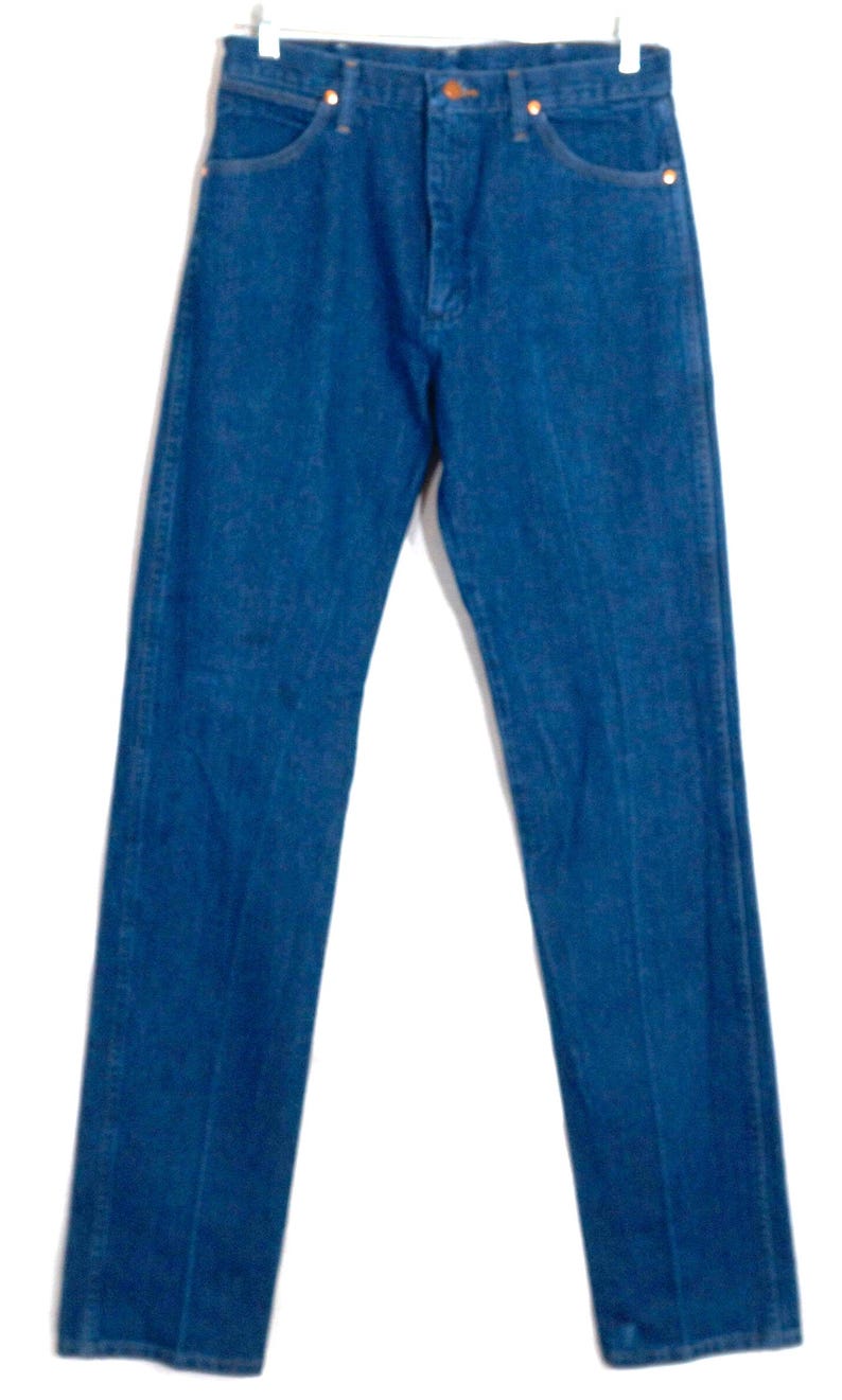 May include: A pair of blue denim jeans with a straight leg. The jeans have a classic five-pocket design, a button and zip fly, and copper-coloured rivets. The denim has a medium wash and a slight fade, giving them a vintage appearance.