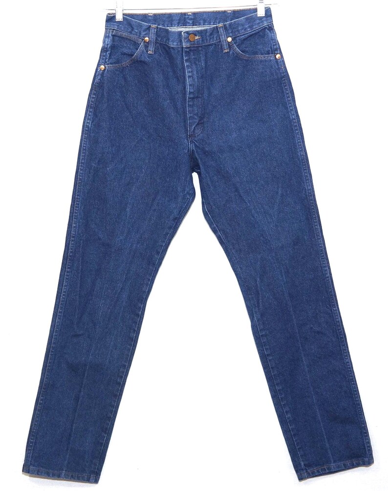 May include: Dark blue denim jeans with a classic five-pocket design. The jeans have a button and zip closure, and are hanging on a white hanger. The jeans are a straight-leg style.