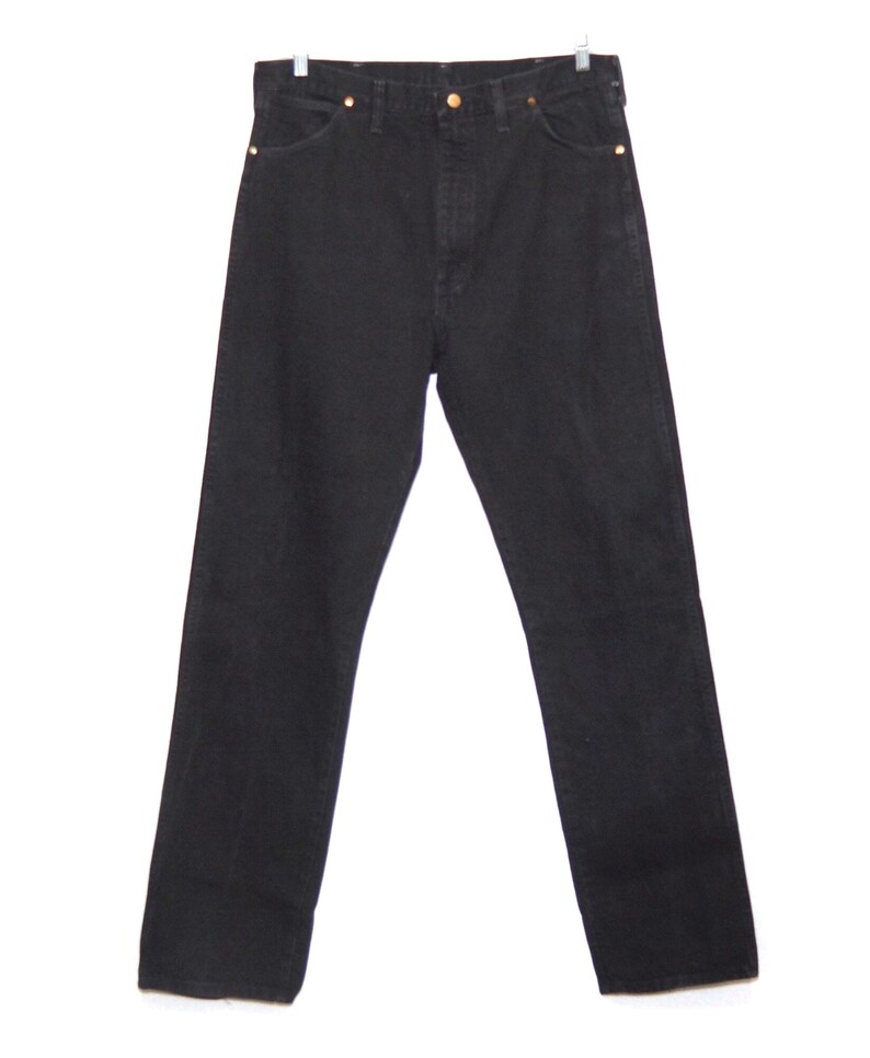May include: Black denim jeans with a classic five-pocket design. The jeans have a straight leg cut and are hung on a metal hanger. The rivets and button are a gold color.