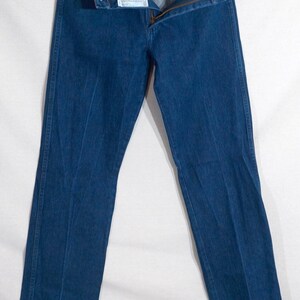 May include: Dark blue denim jeans with a zip fly and button fastening. The jeans are straight-legged and have a classic five-pocket design. The jeans are displayed against a white background.