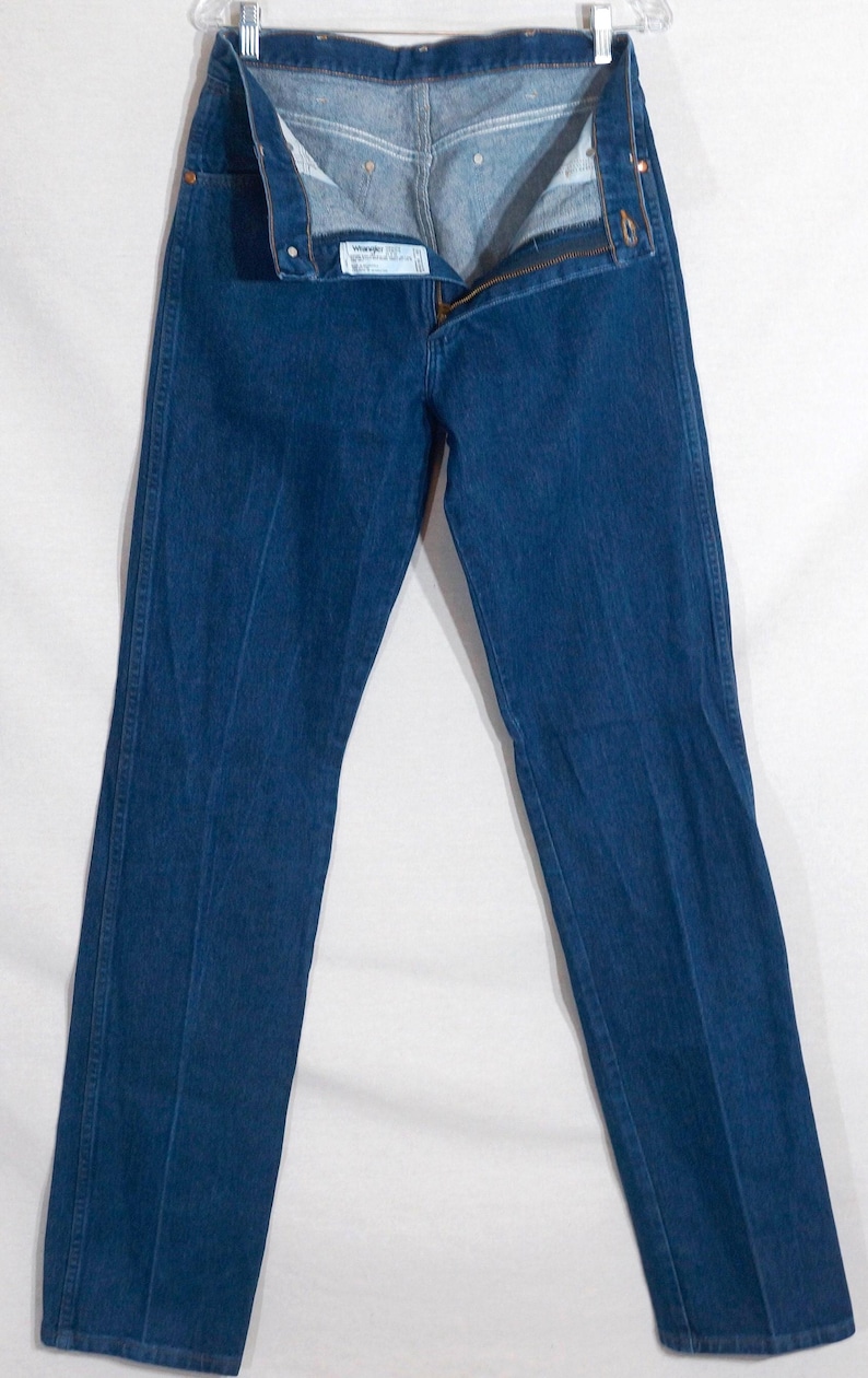 May include: Dark blue denim jeans with a zip fly and button fastening. The jeans are straight-legged and have a classic five-pocket design. The jeans are displayed against a white background.