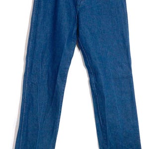 May include: A pair of classic blue denim jeans. The jeans have a straight leg cut, five pockets, and a button and zipper closure. The jeans are hanging on a wooden hanger against a white background.