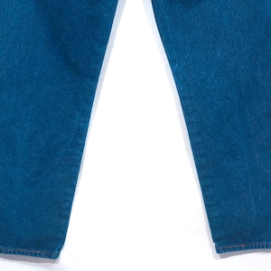 May include: Close-up of blue denim jeans. The jeans have a classic straight leg cut and a medium wash. The fabric appears to be sturdy, with visible texture. The hem is finished with a simple, clean stitch.