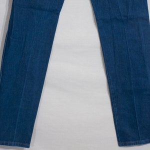May include: A pair of straight-leg blue denim jeans. The jeans have a classic five-pocket design, with a button and zip closure. The denim is a medium wash, and the jeans appear to be unworn.