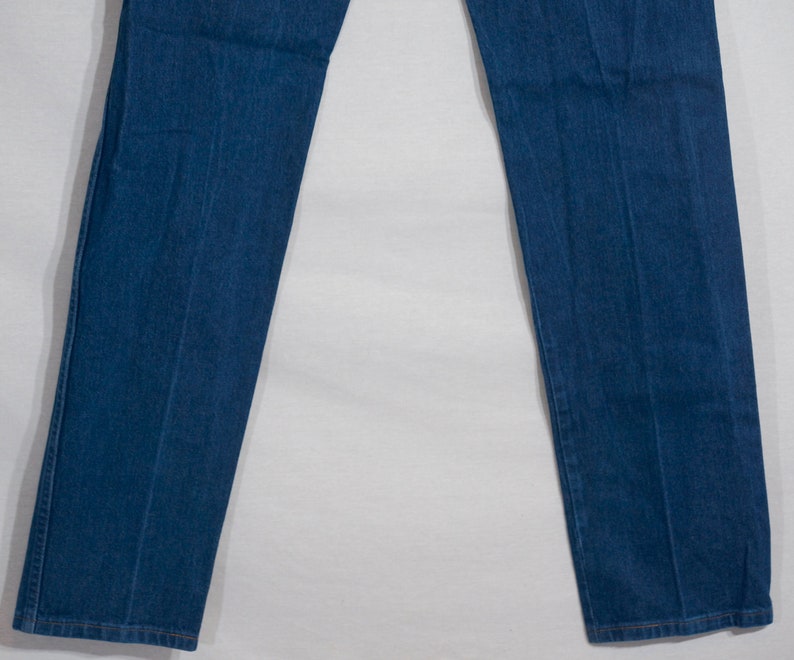 May include: A pair of straight-leg blue denim jeans. The jeans have a classic five-pocket design, with a button and zip closure. The denim is a medium wash, and the jeans appear to be unworn.