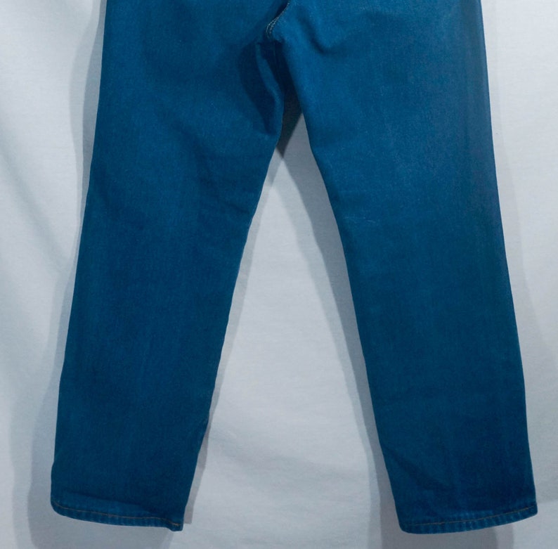 May include: A pair of blue denim jeans. The jeans have a classic five-pocket design and a straight leg fit. The denim is a medium wash, and the jeans appear to be new or in excellent condition.