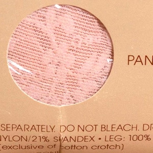 May include: Close-up of a package with a circular window revealing pink lace fabric. The text "PANTY COLOR" is visible, along with care instructions and fabric composition details.