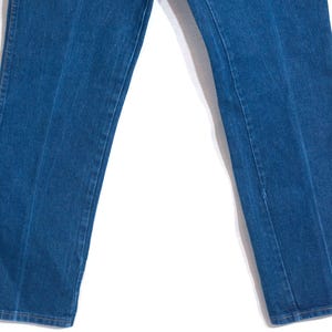 May include: Close-up of blue denim jeans. The jeans have a classic straight-leg cut and feature a visible seam down the front of each leg. The denim has a medium wash and a slightly faded appearance.