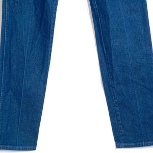 May include: Close-up of blue denim jeans. The jeans have a classic straight leg cut and a medium wash. The seams are visible, and the fabric appears to be sturdy. The jeans are a staple in casual wear.