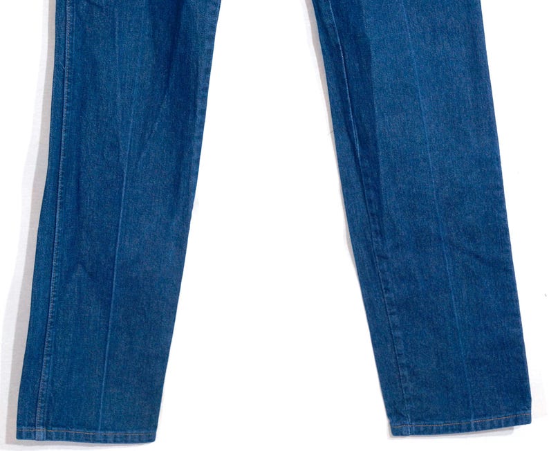 May include: Close-up of blue denim jeans. The jeans have a classic straight leg cut and a medium wash. The seams are visible, and the fabric appears to be sturdy. The jeans are a staple in casual wear.