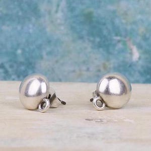 Op de afbeelding: Een paar zilveren bolvormige oorbelletjes met een gladde, gepolijste afwerking. De oorbelletjes hebben een eenvoudig, minimalistisch ontwerp.
