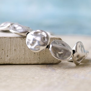 May include: A silver bracelet with round, textured beads.