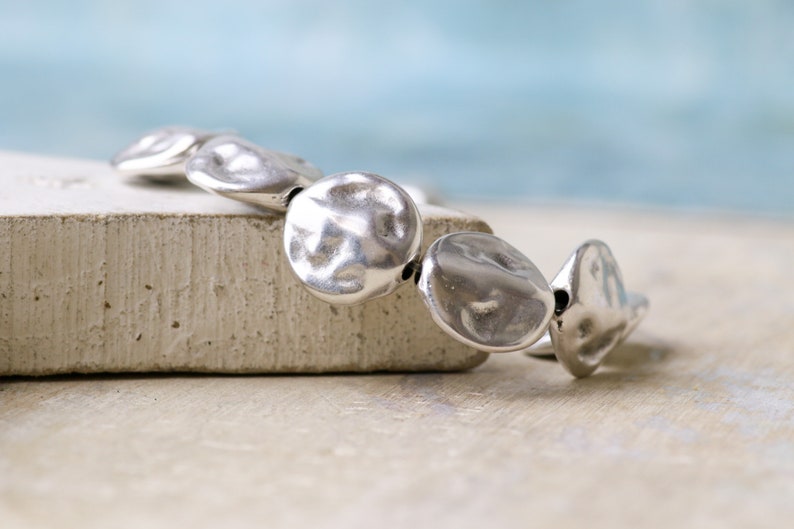 May include: A silver bracelet with round, textured beads.