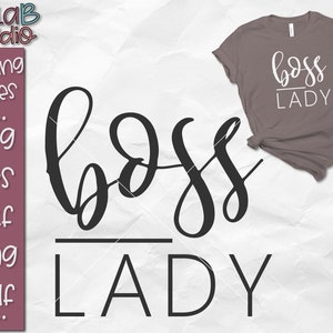 以下が含まれることがあります： 白い背景に、黒い文字で「boss lady」と書いてあります。文字は黒い線で区切られています。背景には、同じ文字が白で書かれた灰色のTシャツが表示されています。