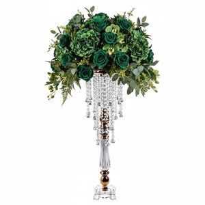 Puede incluir: Un centro de mesa alto con un arreglo denso de rosas, hortensias y follaje de eucalipto en color verde esmeralda oscuro sobre un soporte de acr&iacute;lico transparente adornado con cuentas de cristal que cuelgan de la base del ramo.