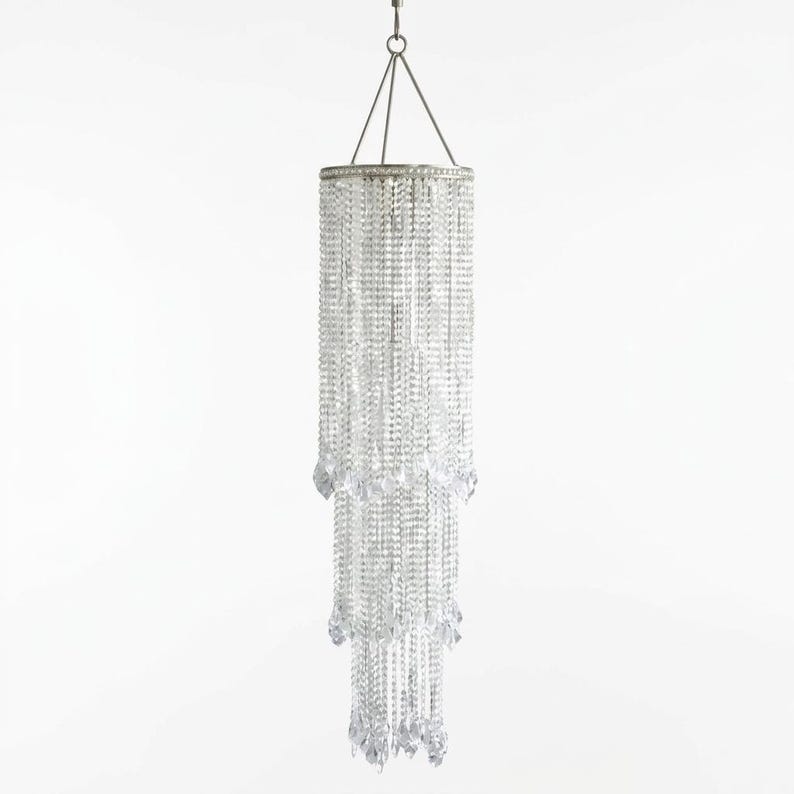 May include: A tiered cylindrical chandelier featuring multiple strands of clear, faceted crystal beads suspended from a circular silver-toned metal frame. The fixture hangs from a central wire and tapers into three distinct, layered sections.