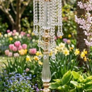 Puede incluir: Un candelabro alto y esbelto con un tallo de vidrio transparente con estr&iacute;as verticales, acentuado por secciones de metal dorado. La plataforma circular superior est&aacute; adornada con m&uacute;ltiples hileras de cuentas de cristal transparente facetado.