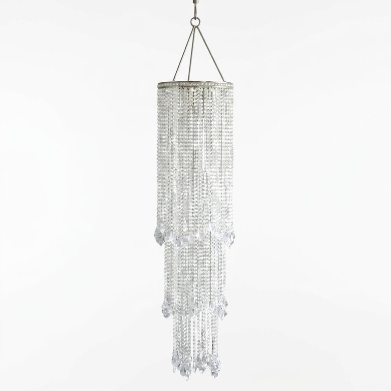 May include: A tiered cylindrical chandelier featuring multiple strands of clear, faceted crystal beads suspended from a circular silver-toned metal frame. The fixture hangs from a central wire and tapers into three distinct, layered sections.
