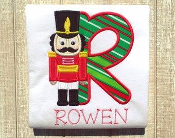 May include: White t-shirt with a red and green striped letter R, a nutcracker illustration, and the name "ROWEN" embroidered in red.