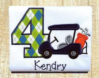 May include: White t-shirt with a navy blue golf cart and an orange golf bag. The number 4 is in argyle pattern with green and blue diamonds. The name "Kendry" is embroidered in navy blue.