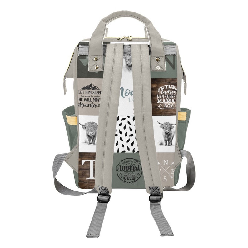 May include: Gray and white backpack with a patchwork design featuring Highland cows, text, and geometric patterns. The backpack has adjustable straps, multiple pockets, and a top handle. The text includes phrases like "Let Him Sleep" and "Future Mama Boy."