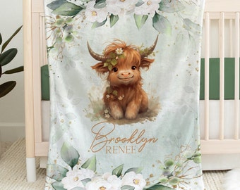 May include: A soft, blue and green baby blanket with a cute cartoon highland cow wearing a flower crown. The blanket has a white floral border and the name "Brooklyn Renee" is written in gold script.