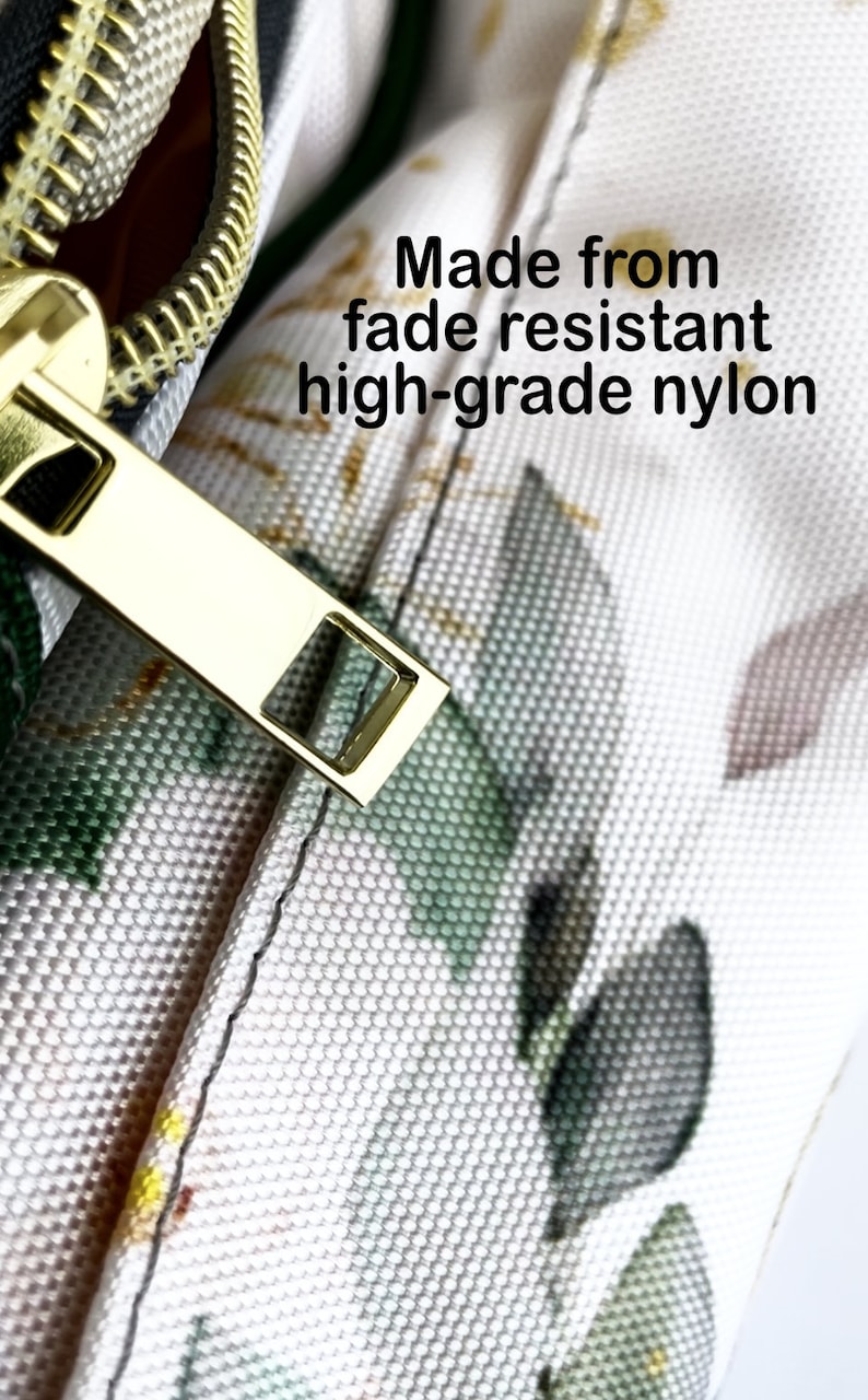 May include: Close-up of a section of a bag with a gold zipper and a floral pattern. The bag is made from fade-resistant, high-grade nylon. The zipper is open, revealing the interior.