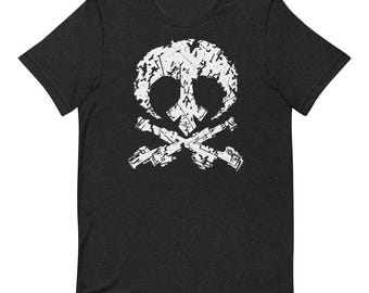 May include: A charcoal gray short-sleeve t-shirt featuring a white distressed graphic on the chest. The design depicts a stylized skull shape combined with two crossed blaster-style weapons, creating a bold, weathered, and textured appearance.