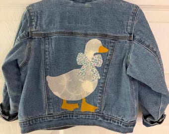 Chaqueta vaquera Goose de mezclilla reciclada para niña talla 2T con aplique de lazo.