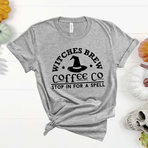 May include: A gray t-shirt with a black graphic that says "Witches Brew Coffee Co. Stop in for a spell". The graphic features a witch's hat with a star on each side.